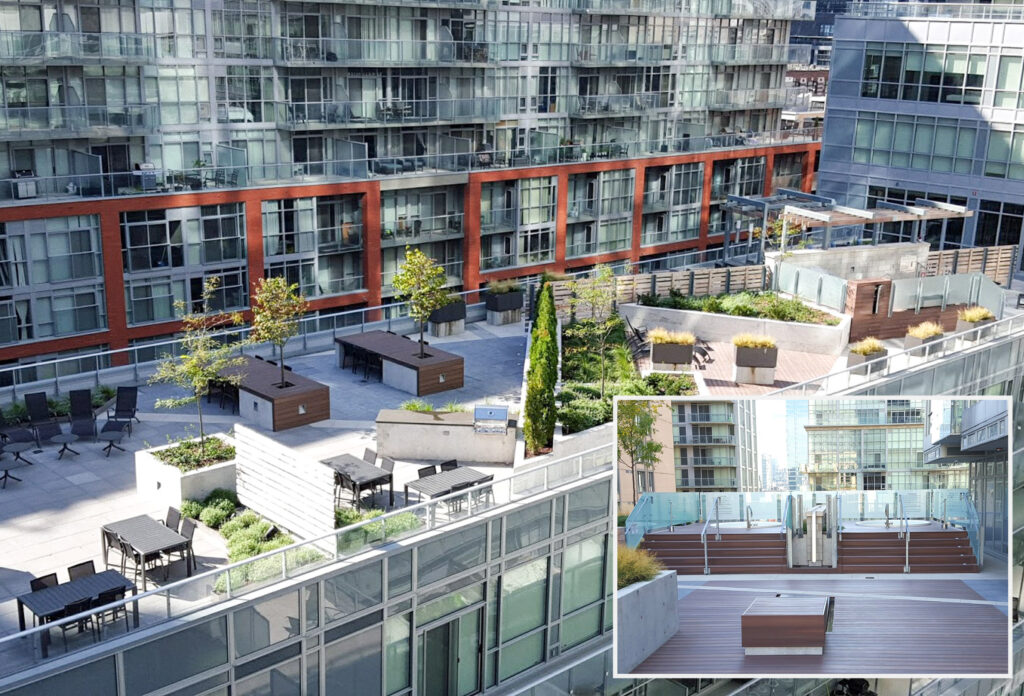 Commercial Decking by Delta Decks: Aerial view of a modern apartment complex with glass facades. Rooftop features a garden terrace with planters, trees, benches, and tables. Surrounding buildings have multiple stories and large windows, contributing to a sleek urban cityscape.