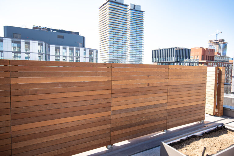 A modern balcony with wooden privacy screens and a view of contemporary buildings in the background.