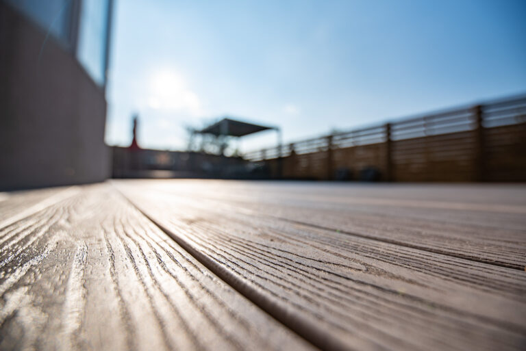 Spacious backyard deck with patio furniture, seating area under a canopy, and wooden privacy fence on a sunny day.
