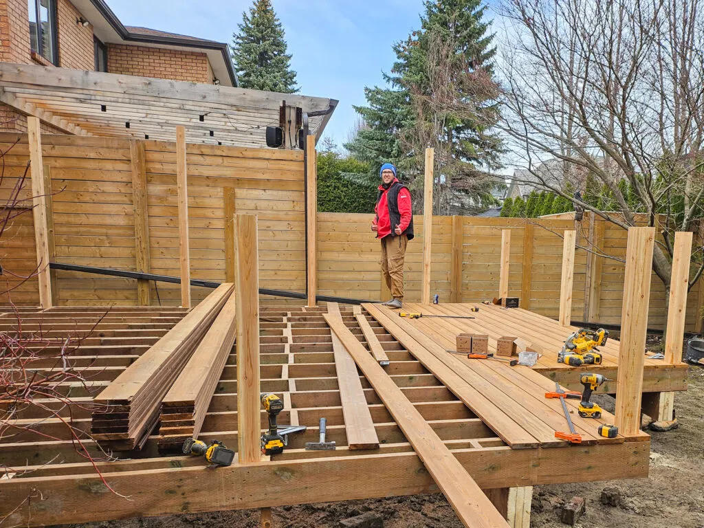 Construction worker building wooden deck in backyard