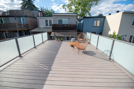 Finished rooftop deck with composite boards, glass railings and a Toronto neighbourhood view